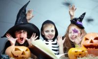 bambini vestiti per Halloween davanti a zucche  e un libro aperto