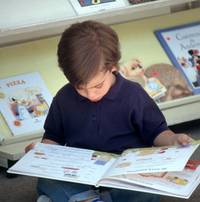 bambino che legge seduto in biblioteca