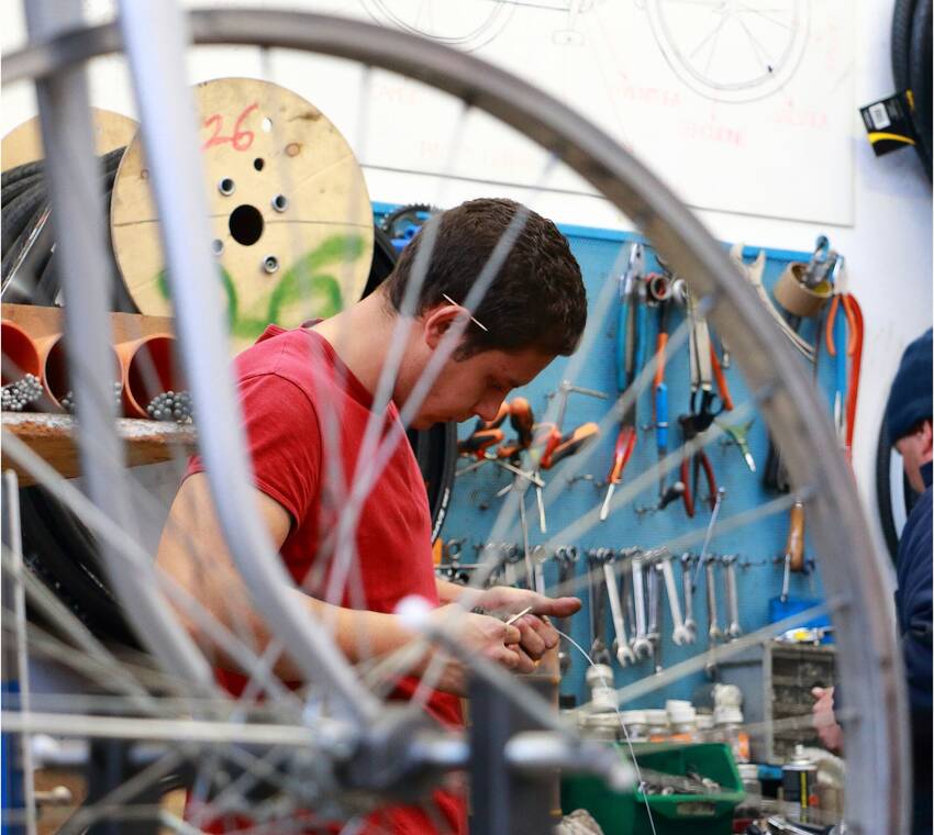 fotografia che ritrae ragazzo che ripara una bicicletta (foto Silvano Brun)