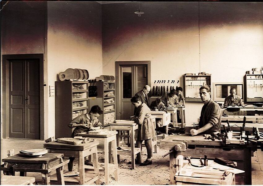 Fotografia in banco e nero: Luigi Mozzani all'interno della liuteria con i propri dipendenti al lavoro (ca. 1942-1943)